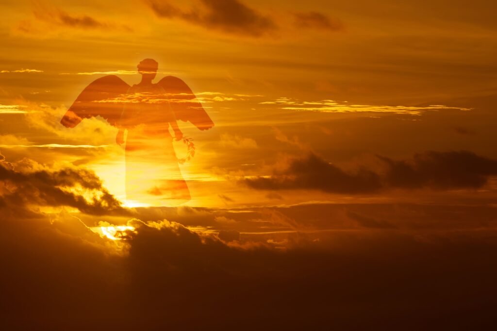 Silhueta de um anjo em um céu alaranjado.